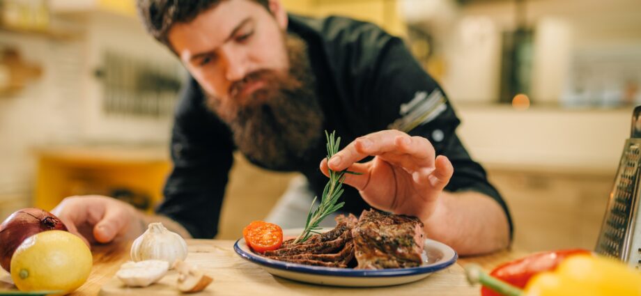 Chef decorates herbs roasted meat slices in plate