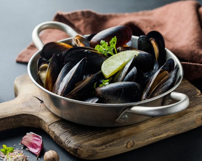Seafood. Shellfish mussels. Baked mussels on cast iron black plate