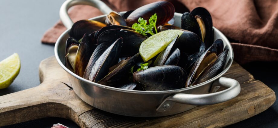 Seafood. Shellfish mussels. Baked mussels on cast iron black plate